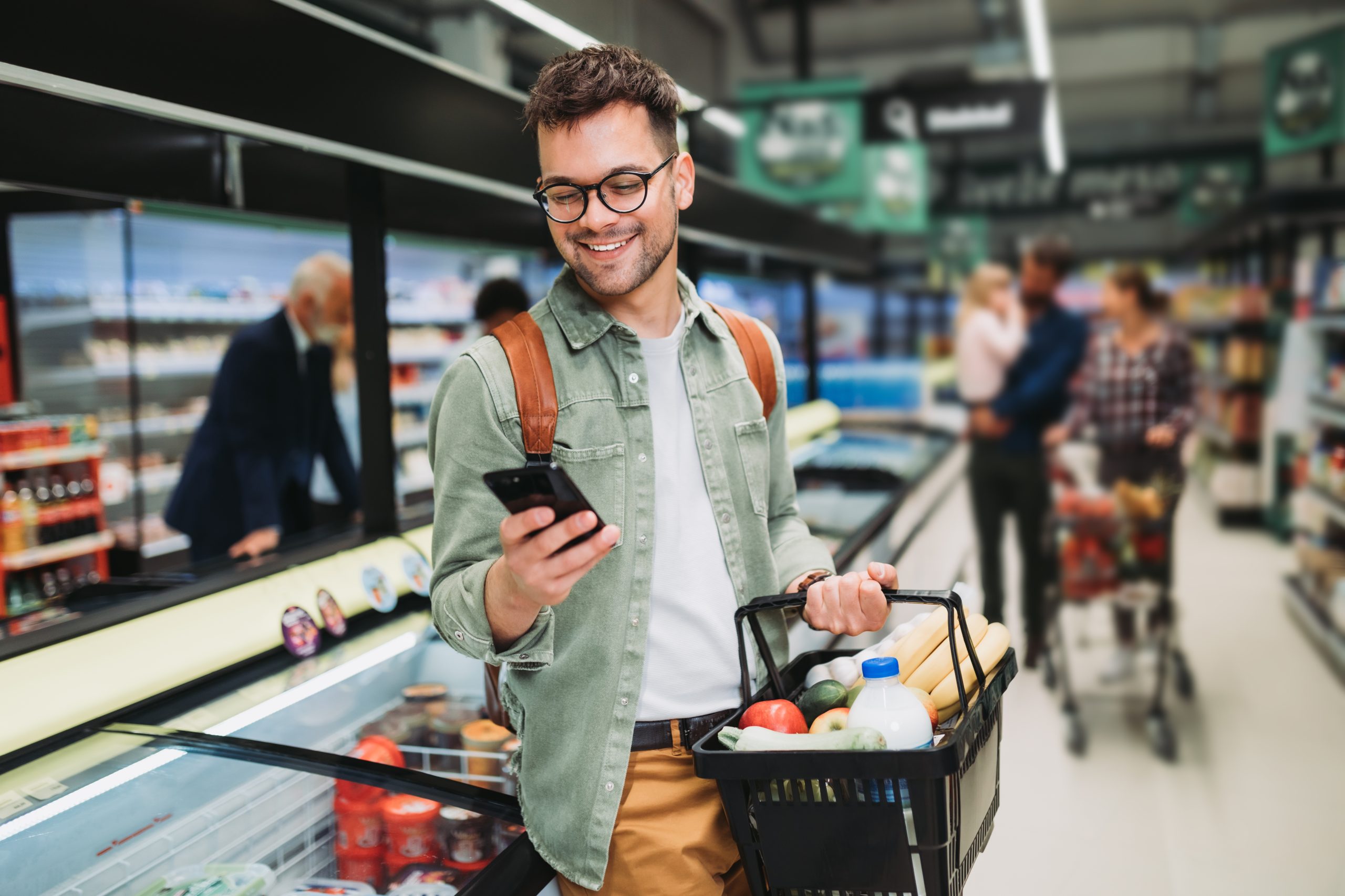 Young,Man,Buying,Groceries,At,The,Supermarket.,Other,Customers,In